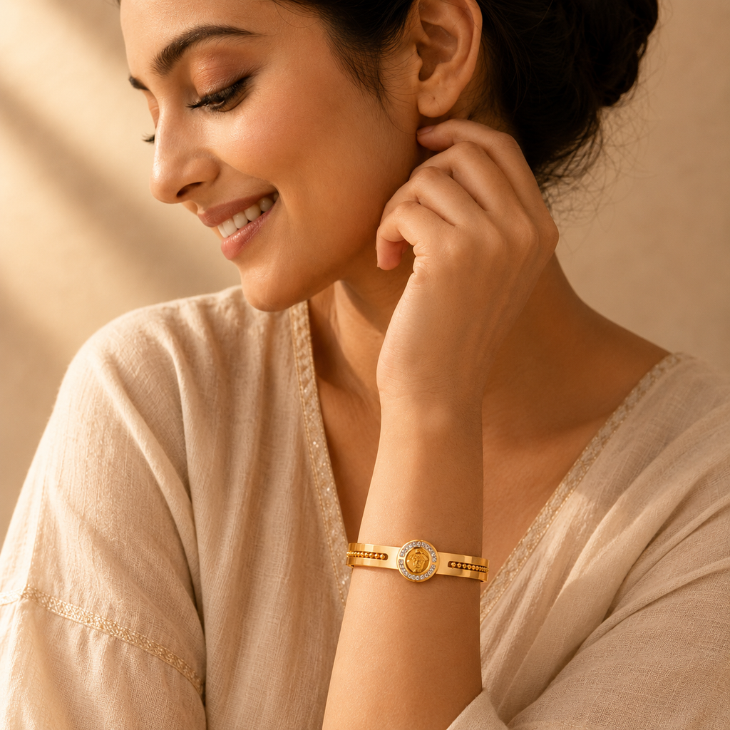 Woman wearing a gold-plated statement bangle bracelet in a warm, softly lit portrait