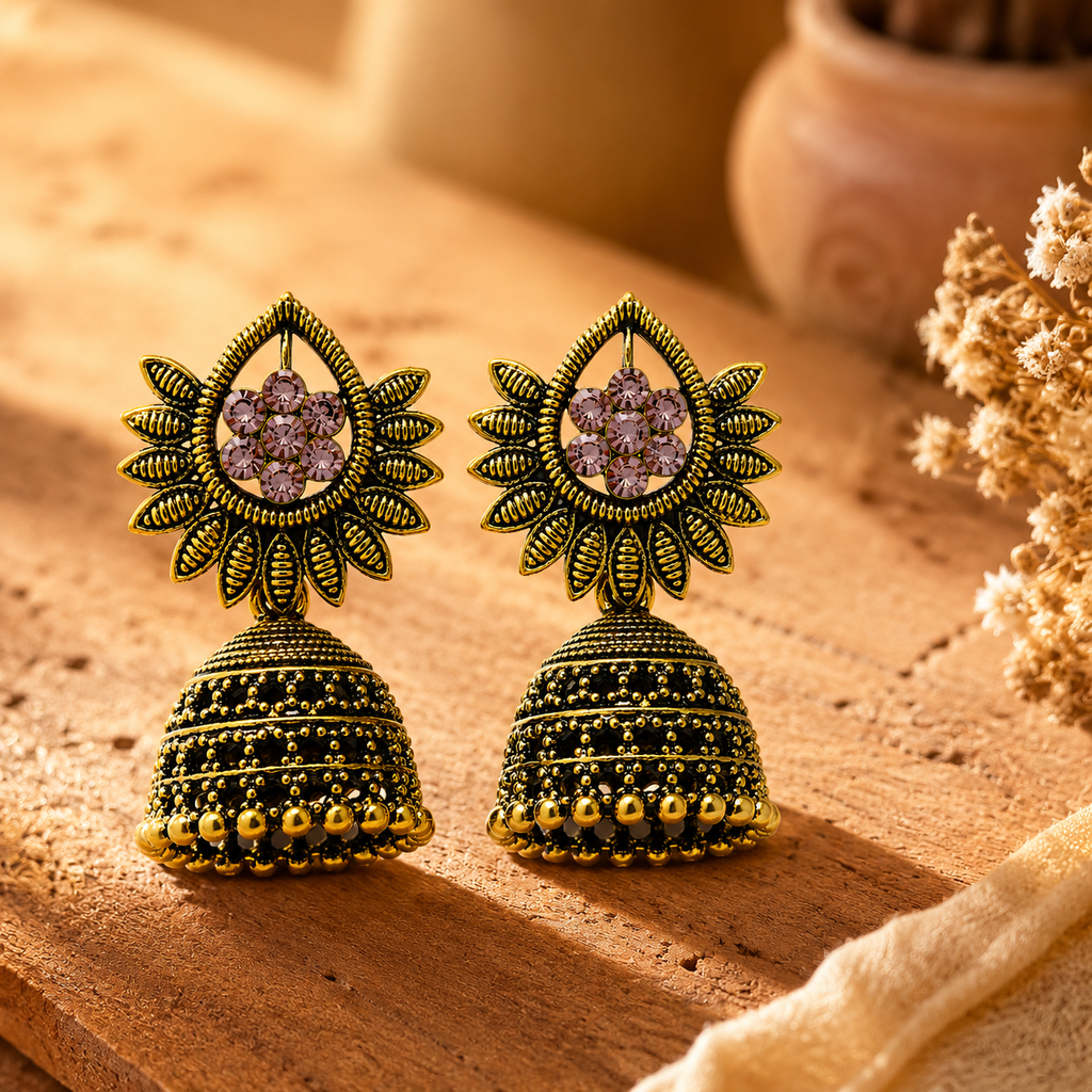 Antique gold pink stone sunburst jhumka earrings styled on wooden surface