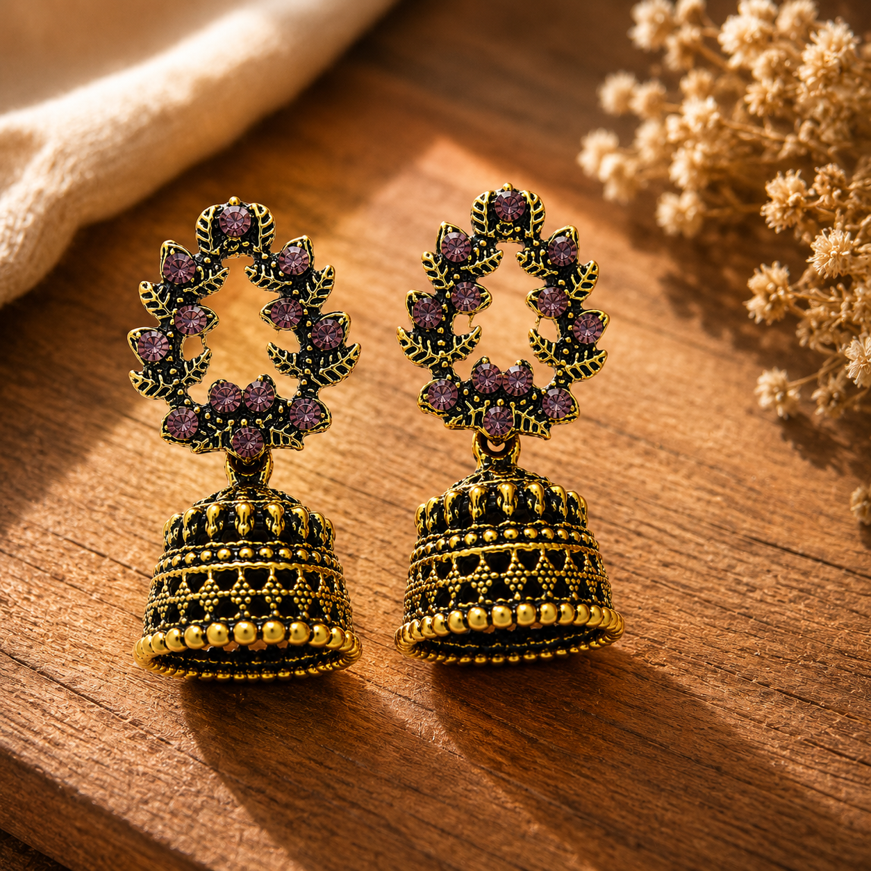 Antique gold purple stone jhumka earrings styled on wooden surface
