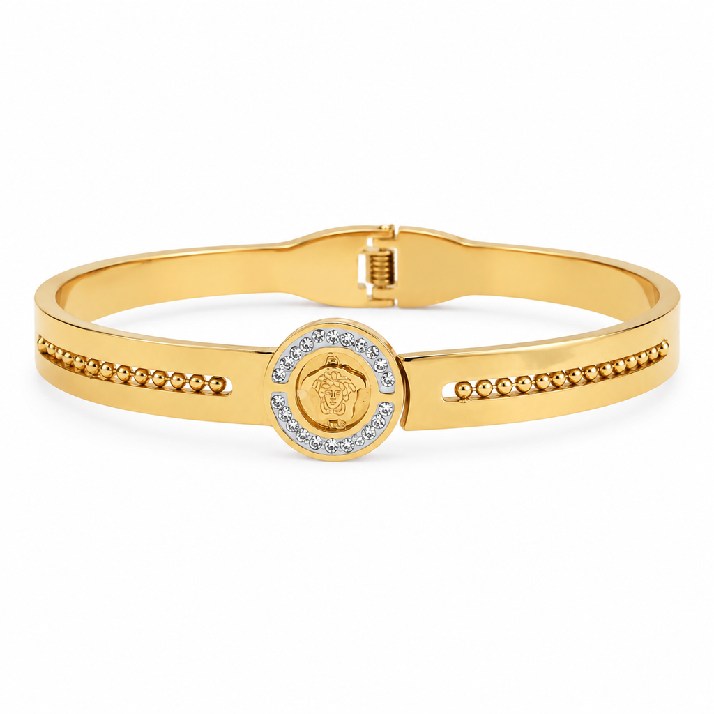 Gold-plated medallion bangle bracelet resting on a wooden surface