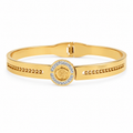 Gold-plated medallion bangle bracelet resting on a wooden surface
