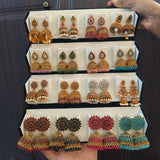 Hand holding an open black velvet box with 16 pairs of antique gold jhumka earrings – Jaan Creations