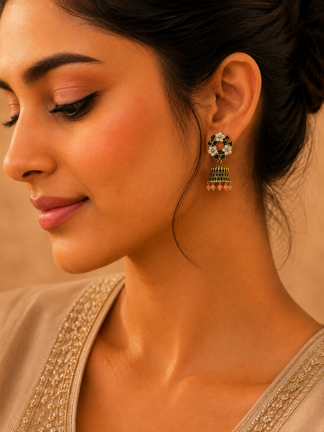 A close-up lifestyle shot of a woman wearing a traditional Indian jhumka earring. The earring features a floral top with white stones, a green beaded middle section, and dangling pink bead tassels.