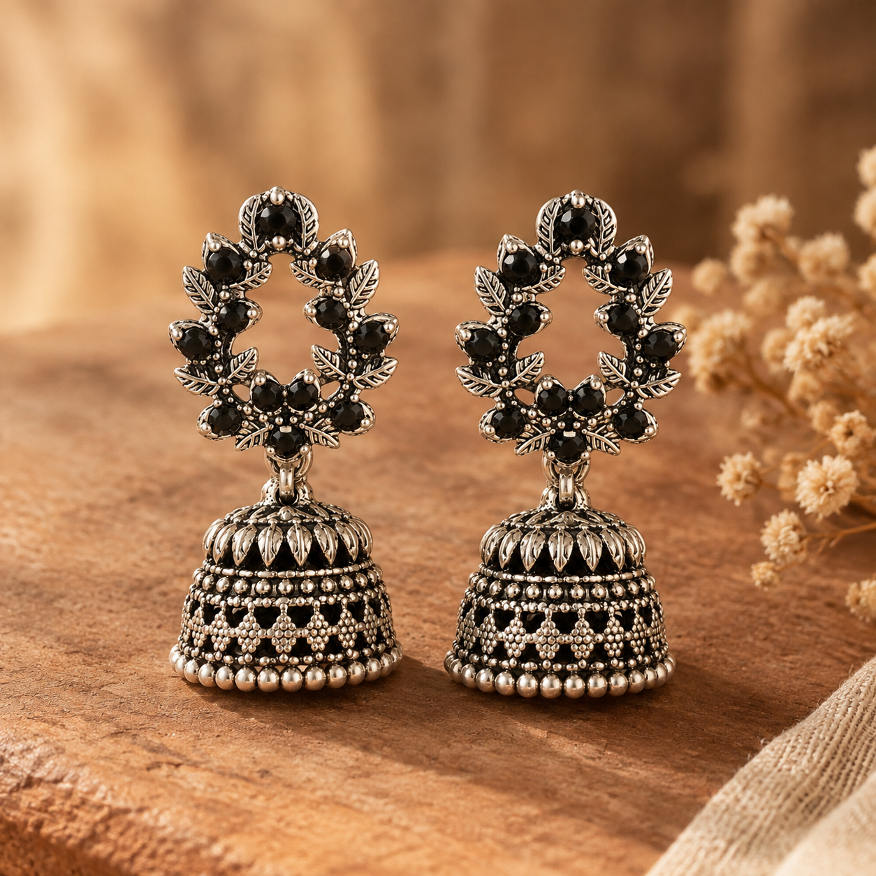 Close-up of a silver oxidised jhumka earring with black stone and leaf wreath stud