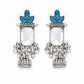 A pair of ornate silver-toned statement earrings featuring a large clear rectangular central stone, blue teardrop-shaped stones at the top, and detailed silver filigree and beadwork below, shown on a plain white background.